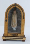 Capela portuguesa em madeira, porta envidraçada com moldura em baquelite, interior com imagem de Nossa Senhora de Fátima. Mecanismo musical a corda, precisa revisão. Med. 21 x 13 x 8 cm.