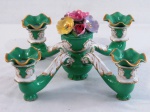 VISTA ALEGRE- Imponente candelabro baixo em porcelana portuguesa, com quatro braços na cor verde esmeralda, decorada com flores em relevo e policromia. Acompanha três bobeches onduladas com frisos dourados. Marcado. Med. 17 cm alt x 37 cm diâmetro. Obs: Com antigo restauro ( colado) nos braços e bicados.