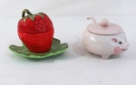 Duas (02) peças em faiança policromada sendo: uma no formato de morango  em faiança Weiss ( 12 x14 cm), uma farinheira em porcelana pintada a mão no formato de porco ( 10 x 12 cm.)