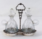 Elegante galheteiro em metal espessurado à prata, galhetas em demi cristal lapidado com folhagens. Med. 18 x 19 x 9 cm.