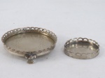 Duas (02) pequenas salvas em metal espessurado a prata, uma tripóide com pés em garra, fundo cinzelado e cercadura vazada. Med. maior11 cm diâmetro, menor 7 cm diâmetro.