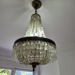 Belíssimo lustre estilo império francês com armações circulares em bronze para quatro lâmpadas, ricamente lavrados com volutas e folhagens, pingentes em cristal europeu ricamente lapidados. Med.: 65 x 40 cm. Obs: Alguns cristais se soltando.