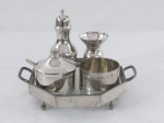 Conjunto com cinco (05) peças em pewter polido sendo: bandeja oitavada com alças laterais sobre quatro pés, base em vidro ( 18 cm diâmetro), saleiro ( 12 cm alt), pimenteiro com colher, paliteiro, pote para molho sem tampa.