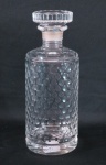 Garrafa para whisky em bloco de cristal translúcido europeu, corpo cilíndrico, decorada com escamas, pega da tampa facetada. Med. 26 cm alt x 9 cm diâmetro.