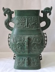 CHINA Séc. XIX-  Imponente vaso de ritual chinês em ferro no tom verde escuro, estilo arcaico, decorado com três faixas com gregas e arabescos, finalizadas embaixo com máscara Taotie figura do neolítico chinês em relevo. Alças laterais estilizadas com cabeças de Xiling. Furadas na base. Assinada na base JW ( em virtude do furo não dá para verificar o restante da assinatura) Med. 39 x 31 x 25 cm.
