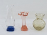 Três (03) vasos em vidro de tamanhos e modelos diversos, sendo um base quadrangular no tom azul ( 18 cm alt), um formato de flor em Murano no tom salmão, borda pinçada ( 13 cm alt), um bojudo craquelado no tom esverdeado ( 11 cm alt).