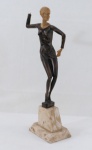 ART DECO- Escultura representando " Bailarina" em resina patinada na cor de bronze, cabeça e mão na cor marfim. Base em mármore rajado. Falta uma mão. Med. 37 cm altura.