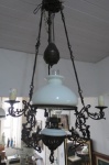 Antigo lustre Colonial estilo lampião em bronze cinzelado para quatro lâmpadas, cúpula de vidro opalinado. Decoração central com chama translúcida, sustentado por correntes e contra peso para regular a altura. Med. 112 x 57 cm. Obs: Um bicado, que não atrapalha a beleza da peça. Lustre muito pesado, só o contra peso 5 kg.