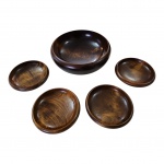 Uma saladeira e 4 pratos em madeira, com marcas de uso, Diam. 14 e 23 x 9 cm.