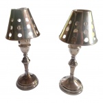 Par de castiçais para uma vela espessurado a prata, com cúpula vazada causando bonito efeito visual, um dele com uma haste solta e outro faltando uma haste, pertenceram ao Hotel Caesar Park, Alt. 32, Diam. 13 cm.