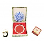COLECIONISMO - Relógio em miniatura Saca, não foi testado, escultura em arroz e  tinta para selo vermelho em caixa de porcelana, Diam. 2 e 6 cm.