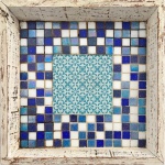 Centro de mesa e/ou fruteira de madeira patinada. Fundo trabalhado em mosaico de azulejos azuis diversos e branco. Formato quadrangular. Mede 37,5 x 37,5cm.