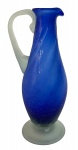 Elegante jarra em vidro artístico soprado de Murano, com delicado corpo em tom azul cobalto translúcido e alça contrastante em opalino leitoso. A peça apresenta suave efeito de torção em sua superfície, revelando o trabalho artesanal do Murano soprado e conferindo movimento e luminosidade ao objeto. Base larga e levemente abaulada garante estabilidade e realça a estética contemporânea. Mede 31 cm altura.Perfeita para compor ambientes sofisticados ou coleções de vidro artístico, destacando-se como elemento decorativo de grande charme e requinte.