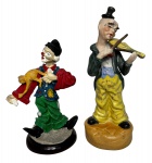 Duo de palhaços policromados, sendo um em resina com pequena perda e outro em biscuit com violino. Medida do maior 18cm.