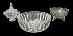 Trio de itens em vidro transparente sendo uma bomboniere com alças e tampa, um bowl e etc. Medida do maior 21cm diâmetro.