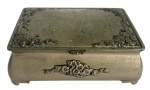 Caixa antiga em metal prateado, decorada com delicados relevos florais nas laterais e tampa. Interior revestido em veludo vermelho. Peça de fino acabamento, ideal para guardar joias ou compor ambientes clássicos e elegantes. Mede 18cm x 13cm.