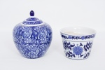 Lote constando de duas peças decorativas em porcelana oriental vitrificada nas cores azul e branco decoradas com flores e folhagens policromadas sendo um cachepot com furo na base para drenagem da água - med. 15x19 cm de diâmetro (com dois bicados na borda da base), e potiche com tampa, pega da tampa na forma de pinha - med. 25x13 cm de diâmetro