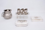 Lote constando de dez peças diversas em metal espessurado a prata e inox sendo um conjunto em inox de bandeja retangular - med. 25x15 cm e seis cálices - med. 8x5 cm de diâmetro, uma jarra em metal espessurado a prata na forma de " saco de dinheiro " , borda ondulada - med. 14x14 cm, uma caixa para cigarros em metal espessurado a prata da manufatura " ST James " - med. 3,5x18x12 cm (banho com desgastes) e uma caixa para charutos Inglesa em metal espessurado a prata, caixa retangular com interior revestido em madeira - med. 4x18x13 cm (banho de prata com desgastes)