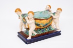 Centro de mesa - Floreira Vintage Italiano em cerâmica craquelê policromada decorada com cesto com guirlanda de flores apoiados por quatro querubins, base retangular med. 22x30x17 cm.