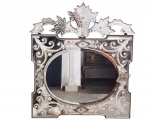 Antigo espelho oval estilo Veneziano, espelho em cristal bisotado com moldura espelhada recortada e bisotado decorado com flores, folhagens e volutas, encimado por florão recortado e decorado - med. 78x70 cm (espelho com desgastes e manchas do tempo, um pequeno bicado na ponta superior do florão, falta três acabamentos de parafusos, madeira central do verso com vestígios de ter tido cupim, precisando ser trocada)