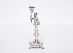 Antigo paliteiro em prata contrastada possivelmente português, representando figura masculina sustentando haste, base quadrada cinzelada e vazada apoiada sobre quatro pés na forma de garras (um dos pés restaurados em metal), med. 19x7x7 cm, peso aproximado 245 gr.