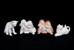 Lote constando de quatro esculturas decorativas em porcelana vitrificadas e policromadas representando dois gatos med. 6x11x4 e 9x10x5 cm e duas esculturas representando casal de cachorros med. 8x9x7 cm.