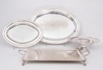 Lote constando de quatro peças, sendo elegante bandeja retangular com alças estilo Inglês. Alças e bordas cinzeladas, apoiada sobre quatro pés de garras med. 7x60x37 cm. Uma fruteira com borda e base cinzelada com folhagens med. 10x32 cm de diâmetro e duas travessas ovais Chilenas com bordas cinzeladas med. 43x31 cm e 58x42 cm (algumas peças com desgastes no banho).