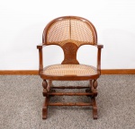 Antiga cadeira de balanço em madeira nobre, encosto curvo entalhado na parte inferior, braços curvos, pernas e base torneadas, encosto e assento em palhinha indiana, mecanismo de molas preservado e funcionando - med. 85x60x70 cm