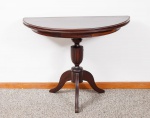Mesa console em madeira nobre, tampo na forma de meia lua reversível para mesa de jantar redonda, coluna central torneada e frisada, apoiada sobre três pés curvos med. 78x107x53 cm (fechada) e 78x107x106 cm de diâmetro (com pequenos defeitos na placagem da folha do tampo).