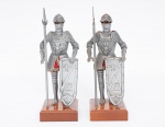 Par de esculturas decorativas representando cavaleiros medievais com armaduras em metal, copos em madeira e rostos em resina, bases quadradas em madeira med. 26x9x9 cm (armaduras com marcas de ferrugem por desgastes do tempo).