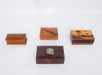 Lote constando de quatro caixas porta jóias em madeira com decorações diversas sendo uma marchetada decorada na tampa com paisagem - med. 6x17x10 cm, uma caixa da Costa Rica com tampa marchetada - med. 5x14x10 cm, uma caixa asiática em madeira entalhada - med. 5x15x7 cm, e uma antiga caixa em madeira nobre com aplicação em prata de lei cinzelado do antigo Brasão da República dos Estados Unidos do Brasil - 1889 - med. 6x18x11 cm (caixas com pequenos desgastes no verniz)