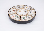 Petisqueira Japonesa da década de 50 em porcelana branca decorada com figuras policromadas e ideogramas, fundo e bordas com frisos a folha de ouro constando de uma peça central redonda e seis recortadas apoiadas sobre bandeja giratória em laca na cor preto, peça central assinada - med. 9x34 cm de diâmetro (borda com pequenos desgastes na laca)