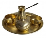 Conjunto de café turco, composto por uma bandeja, um pote de café (cezve), uma tigela com tampa para açúcar ou especiarias e duas pequenas xícaras, em metal dourado com padrões gravados. Medidas 20cm a bandeja,
