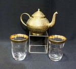 Lote contendo um bule em bronze cinzelado e 2 copos de cristal com bordas e frisos dourados.Bule com 8,5 cm e os copos com 7 cm.