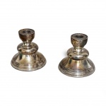 PAR DE CASTIÇAIS EM METAL ESPESSURADO A PRATA, COM BASE EM ONDULAÇÕES, COM BOA FUNDIÇÃO. UM DELES APRESENTA OXIDAÇÃO NA BASE. MEDEM 11A X 12D BASE.