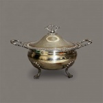 sopeira antiga, identificada como sendo do modelo Regence Laço da renomada manufatura brasileira Fracalanza. Esta peça é feita de metal espessurado a prata (prata 90) e é um ícone da prataria nacional. Marca e Modelo: Fracalanza, modelo Regence Laço. Material: Prata 90 (metal espessurado a prata). Características: Possui alças laterais ornamentadas, uma borda decorada e quatro pés em formato de garra. Uso: Ideal para servir sopas, caldos, feijão, arroz, saladas, doces e compotas medindo 39 x 25