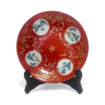 PRATO - Porcelana vermelha com quatro pequenos medalhões representando paisagens policromadas. Japão, diâmetro 15 cm.