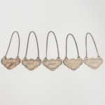 METAL PRATEADO, cinco (5) identificadores para garrafa de bebida, com as legendas: GIN; VERMOUTH;SHERRY; WHISKY; MADEIRA, relevados em volutas e elementos vegetalistas, medindo 7 x 4,5 cm mais a corrente,todos com sinais de uso, vide foto.
