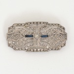 JOIA, um (1) broche, padrão ART DECO, confeccionado em PRATA, cravações em pedras azuis e uma brancacentral lapidação Brasil ou Antique, medindo 4,5 x 2,2 cm, peso aproximado 10,2 gr., contrastado 935 milésimos noalfinete, sinais de uso, vide foto.