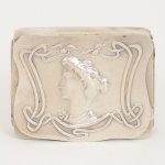 PRATA, uma (1) antiga caixa do período Art Nouveau, tampa ornada com busto feminino perfilado e fitas, versocom marca possessória Alfredo e datação 25-12-907, medindo 4,5 x 3,5 x 1 cm, falta o pino do fecho da tampa, interiorcom resquícios de vermeil, ausência de contrastes, sinais de uso, vide foto., peso aproximado 25,3 gr.