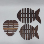 Três descansos para pratos quentes em madeira, na forma de peixes e morango. Comp. 19 a 30 cm.