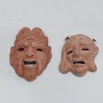 Duas máscaras satíricas em barro cozido. Uma delas quebrada e colada. Med. 11 e 13 cm.