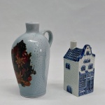 Duas garrafas em porcelana esmaltada em azul e branco. Uma na forma de sobrado, com pequeno quebrado na chaminé. Alt. 9,5 a 13 cm.