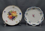 Dois pratos decorativos em porcelana branca: a) Tcheco, borda azul vasada com volutas, decorado com flores e folhagens coloridas. Marcado CZECHOSLOVAKIA. Diam. 19cm. b) Alemão, borda dourada recortada. Decorado com frutos coloridos. Marcado BAVARIA - GEMANY. Diam. 19cm.