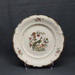Prato decorativo em porcelana polonesa na cor branca, borda dourada recortada, moldada na pasta com volutas e acantos. Decorado com flores e faisão. Marcado KPM. Diam. 27 cm.