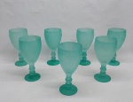 Sete taças para água em vidro verde satinê, base redonda haste com gomos e bojo liso. Alt. 19 cm.