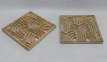 Par de suportes quadrados p/ pratos quentes em metal dourado. Moldado com hastes vasadas. Med. 20 x 20 cm.