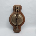 Campanhia para bonde em bronze. Suporte em madeira maciça. Primeira metade do século XX. Med. 35 x 20 cm.
