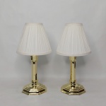 Par de castiçais em metal dourado, base em degrau. Cúpula em pergaminho branco. Alt. total 28,5cm.