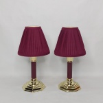 Par de castiçais em metal dourado, base em degraus, coluna octogonal na tonalidade vinho. Cúpula em pergaminho vinho. Alt. total 28,5cm.